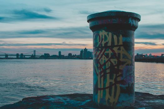 A Graffiti Tagged Pole at Graffiti Pier With the Philadelphia Skyline and a Dramatic Sunset Behind It