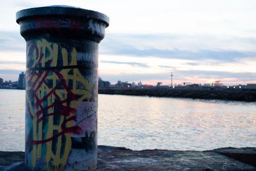 A Graffiti Tagged Pole at Graffiti Pier With the Philadelphia Skyline and a Dramatic Sunset Behind It