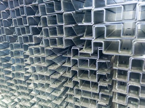 Full frame stack of bended zinc plated sheet steel parts - close-up with selective focus and blur. Sheet bending parts backdrop.