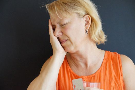 unhappy woman holding her head with her hand, portrait on black background.