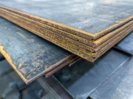 large thick rusted sheet metal stack edge - closeup with selective focus and blur.