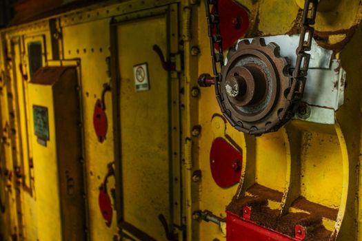 Old rusty cogwheel and chain on a yellow dryer machinery used in tea manufacture factory. General manufacturing concept.