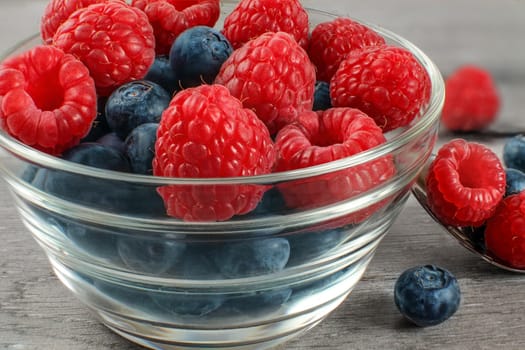 Detail on small glass bowl full of mix of blueberries and raspberries.