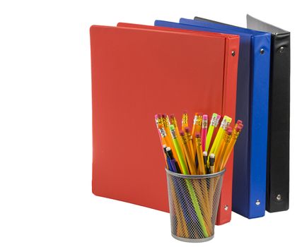 The essentials a student needs for school such as these colorful notebooks and pencils isolated on a white background.