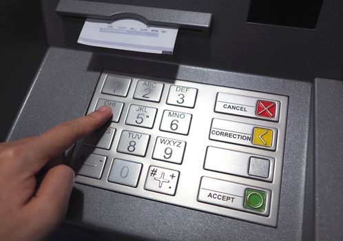 ATM button close-up and paper transaction deposit pay slip and hand.