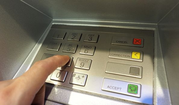 Automatic teller machine or ATM pin button close-up and human hand index finger pushing keypad for withdrawal the money by private personal password banking.