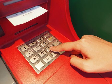 ATM button close-up and paper transaction deposit pay slip and hand.