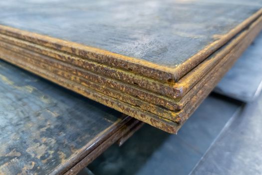 large thick rusted sheet metal stack edge - closeup with selective focus and blur.