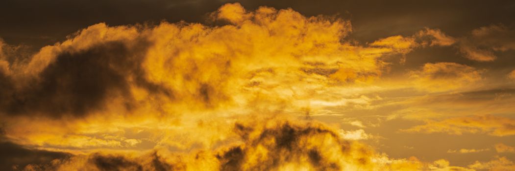 Panorama dramatic clouds illuminated rising of sun in sky to weather change. Natural weather conditions background. Soft focus, motion blur sky cloudscape.