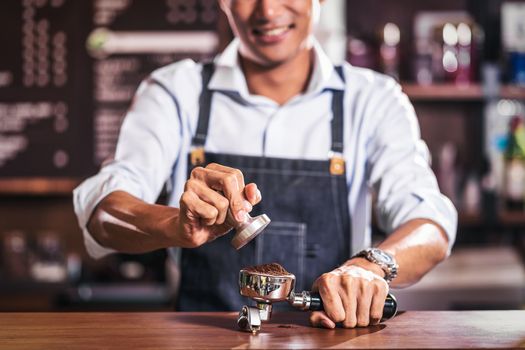Asian Barista tamping the portafilter and preparing cup of coffee, espresso with latte or cappuccino for customer order in coffee shop, Small business owner and startup in coffee shop concept