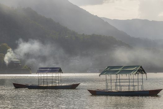 Phewa Lake, Fewa Lake with fog bank or smoke, mist above the water. Background with mountains in Pokhara, Nepal. Panorama and landscape from above.