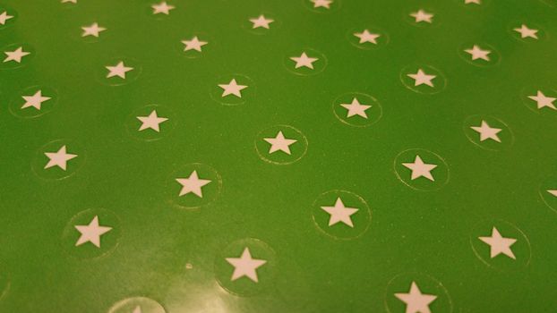 sheet of green paper with white star stickers or labels