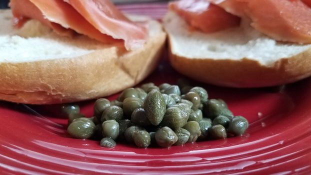 green capers on red plate with bagels and smoked salmon