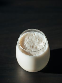 Protein milkshake in tumbler glass over black background. Vertical. Copy space for text or design.