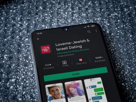 Lod, Israel - July 8, 2020: Loveme app play store page on the display of a black mobile smartphone on a metallic background. Close up top view flat lay.