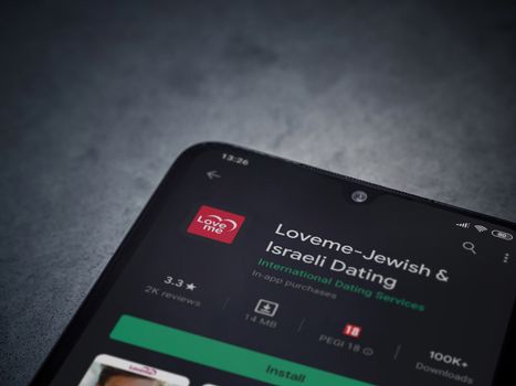 Lod, Israel - July 8, 2020: Loveme app play store page on the display of a black mobile smartphone on dark marble stone background. Top view flat lay with copy space.