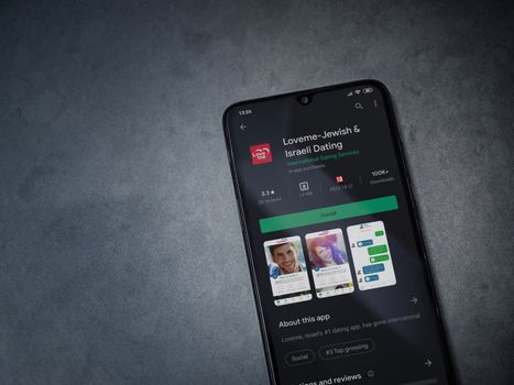 Lod, Israel - July 8, 2020: Loveme app play store page on the display of a black mobile smartphone on dark marble stone background. Top view flat lay with copy space.