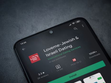 Lod, Israel - July 8, 2020: Loveme app play store page on the display of a black mobile smartphone on dark marble stone background. Top view flat lay with copy space.