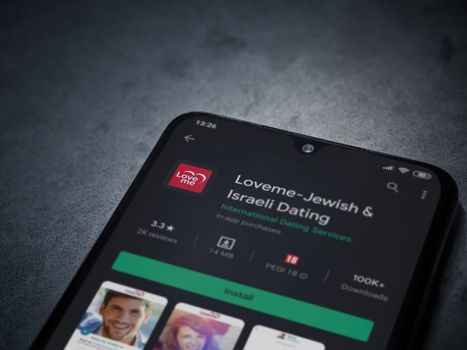 Lod, Israel - July 8, 2020: Loveme app play store page on the display of a black mobile smartphone on dark marble stone background. Top view flat lay with copy space.