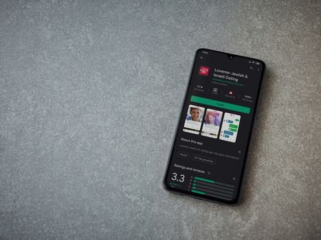 Lod, Israel - July 8, 2020: Loveme app play store page on the display of a black mobile smartphone on ceramic stone background. Top view flat lay with copy space.