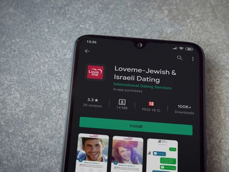 Lod, Israel - July 8, 2020: Loveme app play store page on the display of a black mobile smartphone on ceramic stone background. Top view flat lay with copy space.