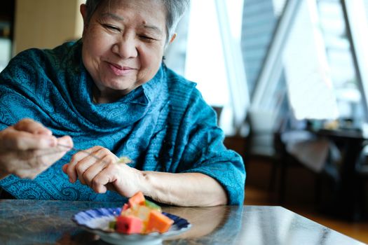 old asian elderly senior elder woman eating fruit at restaurant. mature retirement lifestyle