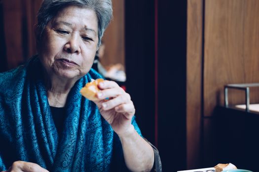old asian elderly senior elder woman eating bread at restaurant. mature retirement lifestyle
