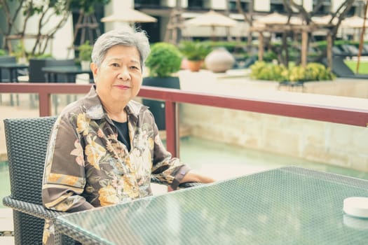 asian elder female woman resting relaxing on balcony terrace at hotel resort. elderly senior leisure lifestyle