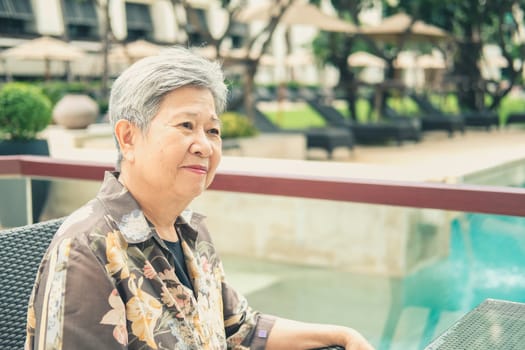 asian elder female woman resting relaxing on balcony terrace at hotel resort. elderly senior leisure lifestyle