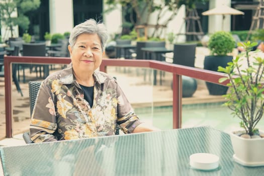 asian elder female woman resting relaxing on balcony terrace at hotel resort. elderly senior leisure lifestyle