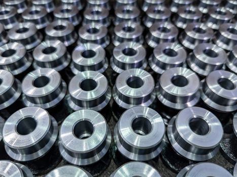 batch of shiny round steel parts background, close-up with selective focus and blur.