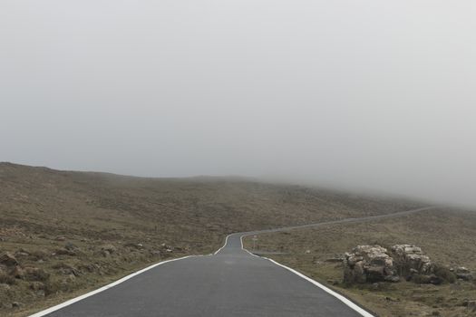 Mountain road going into the fog. Copy space.