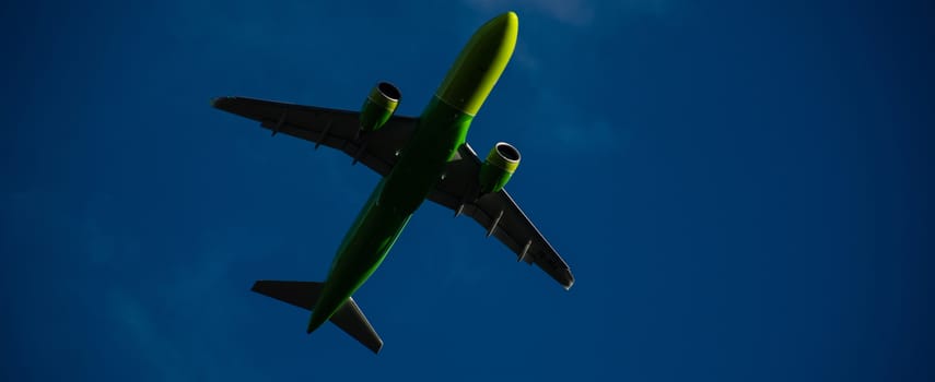 Silhouette of a green plane taking off against a blue sky