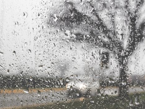 Rainy bad weather on the street. Raining and wet weather driving conditions on the road, traffic blurred, raindrops on car windscreen.