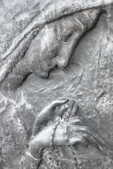 Virgin Mary with rosary. Bas-relief of Our Lady in pray with the sacred rosary.