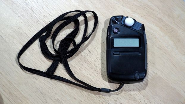 Light meter black color on the wood texture table and top view angle.