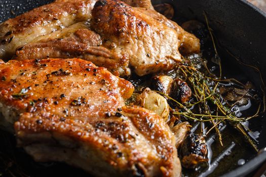 Barbecue Pork Chops on the bone with seasonings and grilled on hot skillet with smoke just from the fire close up side view