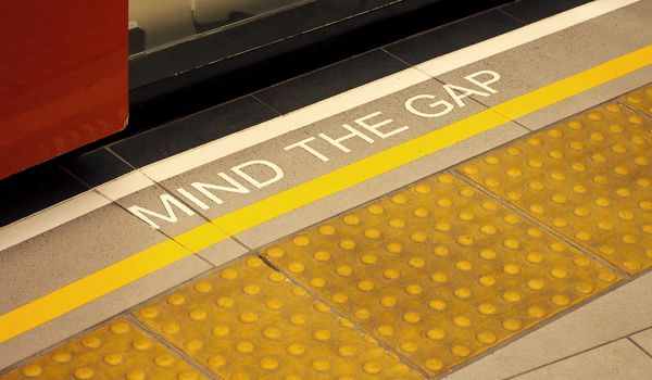 Mind the gap sign on the subway train platform floor and yellow color and dirty and no people.