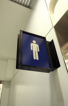 Real toilet sign or restroom direction tab and hanging on the wall and blue color and white icon.