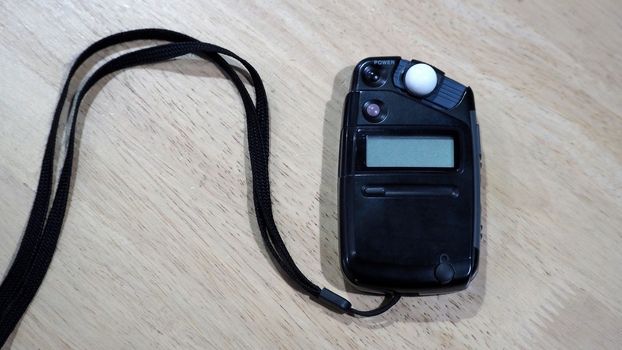 Light meter black color on the wood texture table and top view angle.