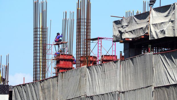 Workers on high building construction site and steel and concrete material.