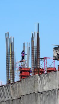 Workers on high building construction site and steel and concrete material.