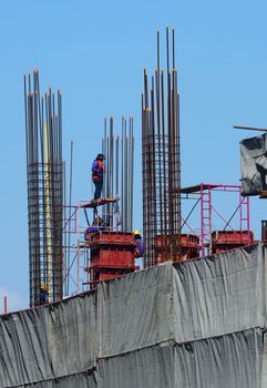 High construction site and labors working and around with concrete cement metal material.