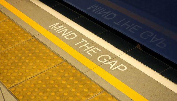 Mind the gap text sign on floor between train and platform station and high angle view.