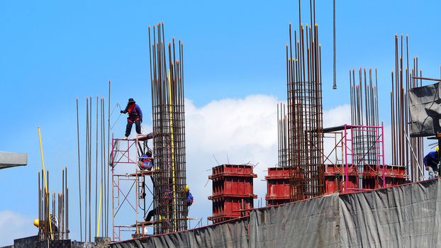 Workers on high building construction site and steel and concrete material.