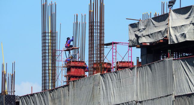 High construction site and labors working and around with concrete cement metal material.