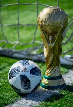 April 9, 2018 Moscow, Russia Trophy of the FIFA World Cup and official ball of FIFA World Cup 2018 Adidas Telstar 18 on the green grass of the football field.