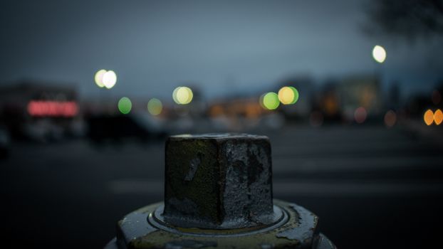 The Top of a Silver Fire Hydrant With a Blurred Shopping Center Behind It
