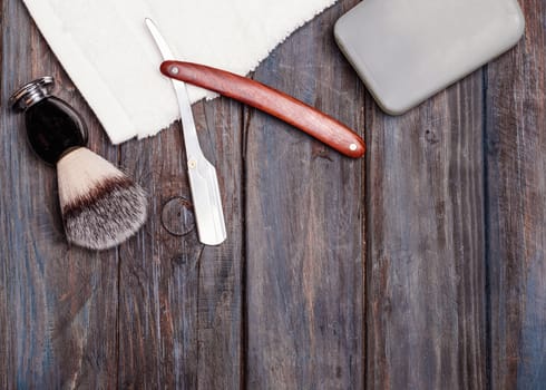 Razor, brush, perfume, towels on a wooden background.