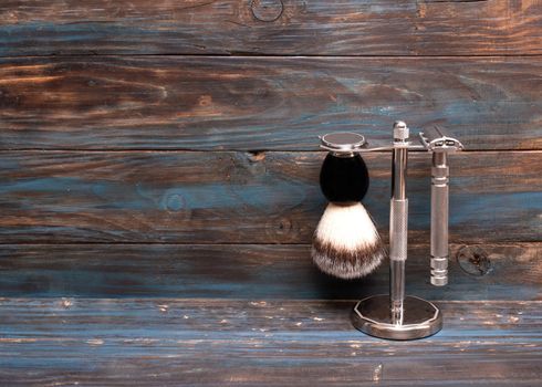 Razor and brush on stand on a wooden background